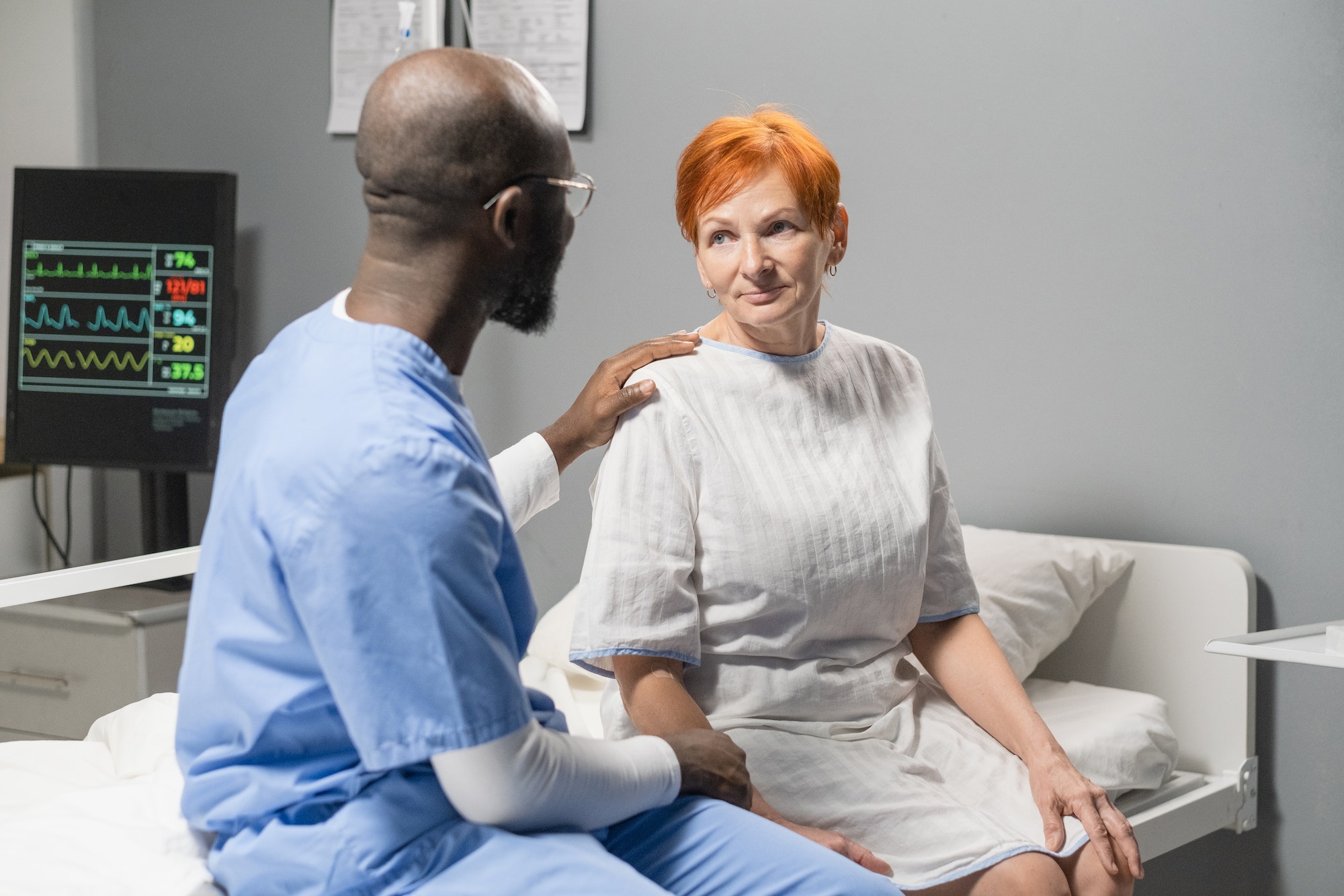 Doctor talking to patient at hospital ward
