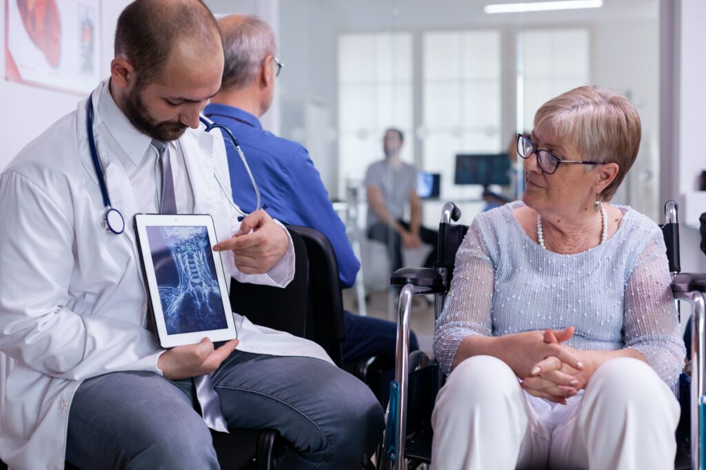 Specialist doctor showing x ray to elderly woman in wheelchair